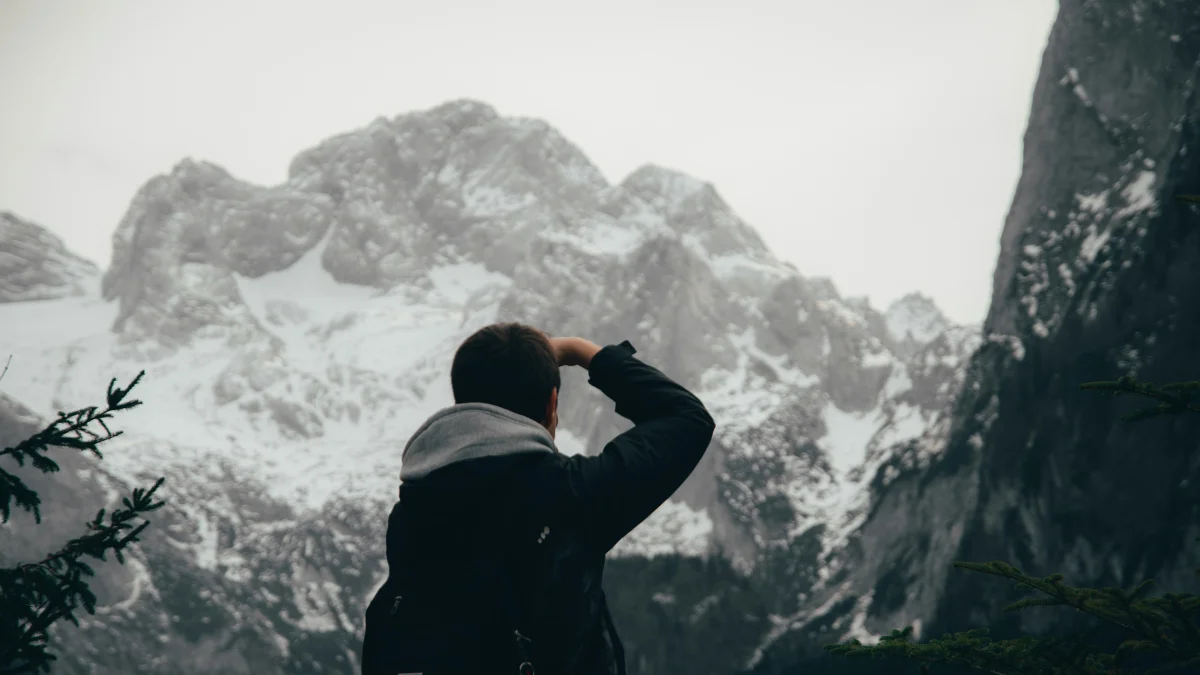 A lone man staring at a mountain peak- Symbolizing the relentless pursuit of impossible goals.
