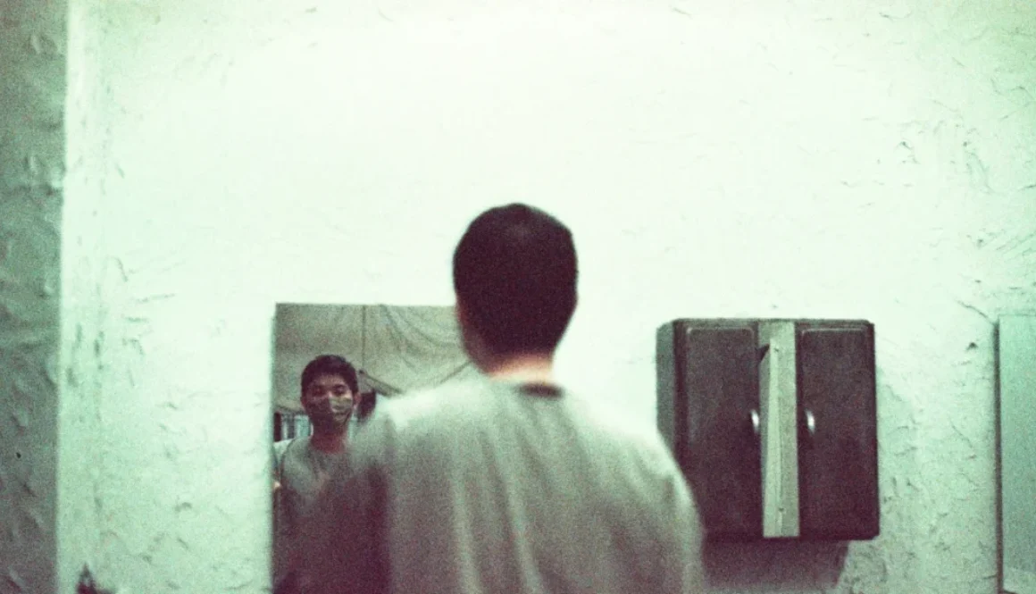 A man looking himself in the mirror & making a conversation, which will help him boost confidence.