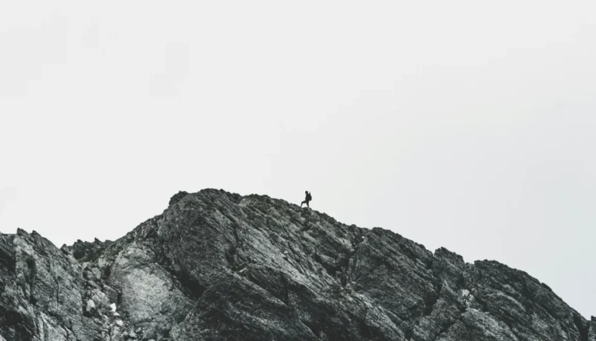 a lone man climbing a mountain