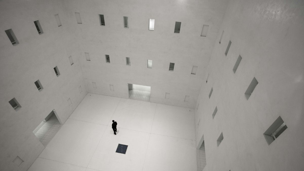 White & Grey tiles A Man standing on the middle of the room, trying to choose between two door
