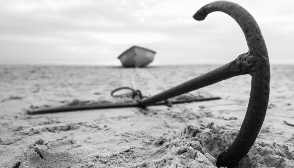 Black and white photo of a boat anchor buried in sand, symbolizing the psychological anchoring effect in decision-making.