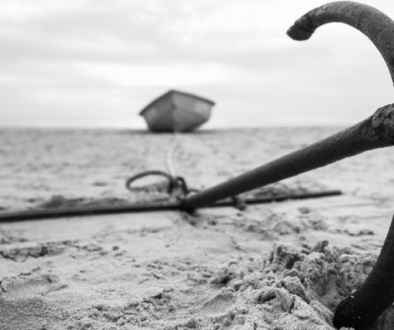 Black and white photo of a boat anchor buried in sand, symbolizing the psychological anchoring effect in decision-making.