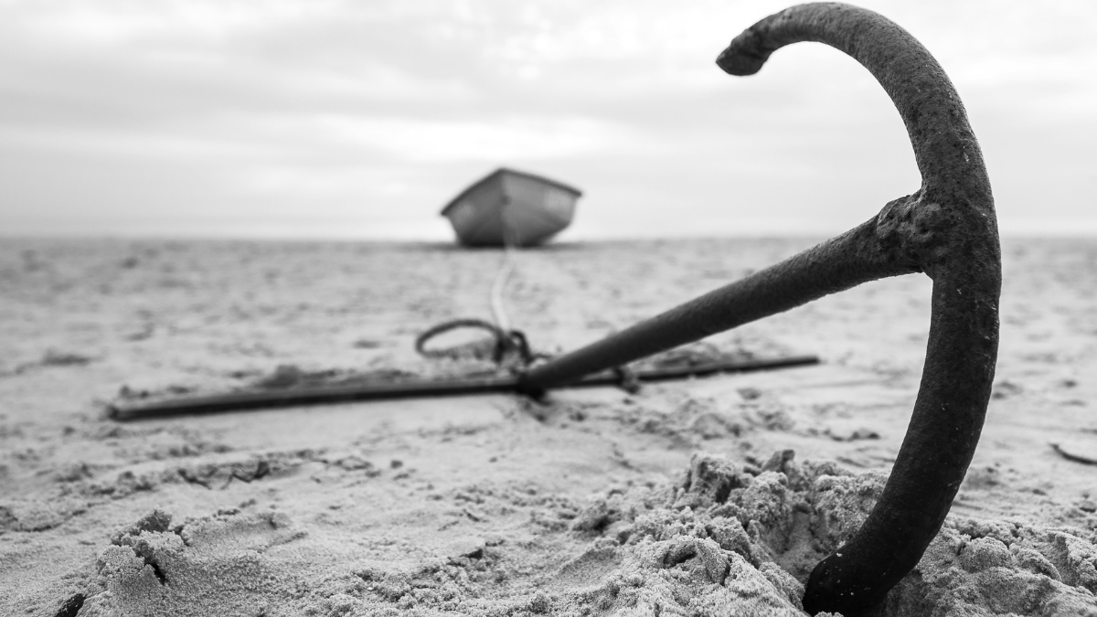 Black and white photo of a boat anchor buried in sand, symbolizing the psychological anchoring effect in decision-making.
