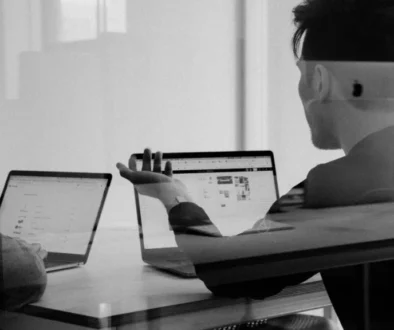 Two people discussing work on laptops, symbolizing overconfidence and misjudgment—key traits of the Dunning-Kruger effect.