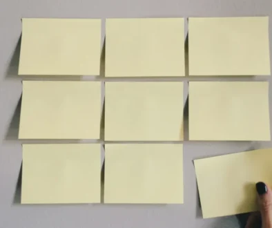 A hand placing the last sticky note on a grid of blank notes, symbolizing the Zeigarnik Effect—our tendency to remember unfinished tasks better than completed ones.