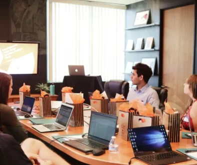 Team meeting with a presenter and laptops on the table, promoting open communication and feedback.